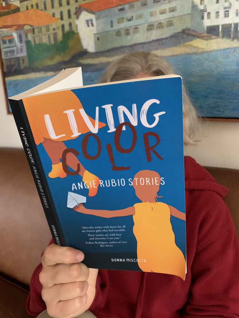 A photograph of me reading Living Color: Angie Rubio Stories.